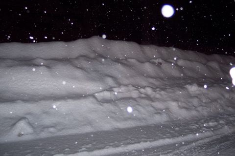2001 Ford Crown Victoria - Snow is falling at night, creating a winter scene with a snow-covered road and bank.