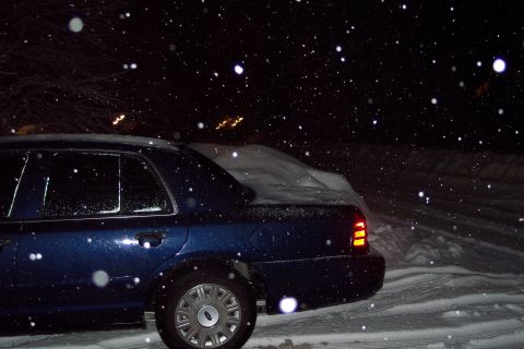 2001 Ford Crown Victoria - A dark blue 2001 Ford Crown Victoria is parked in the snow at night, with snowflakes falling.