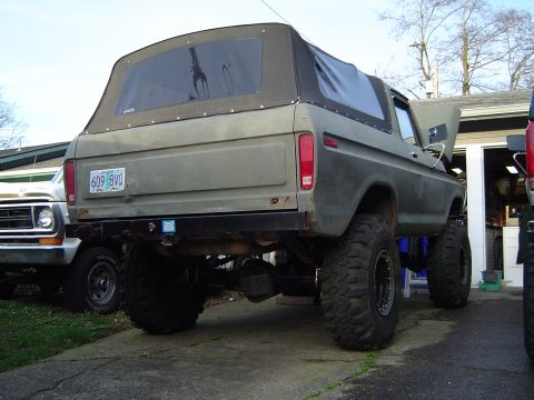 1989 Ford Bronco - Rear view of a lifted 1978 Ford Bronco with a soft top, parked next to another vehicle.