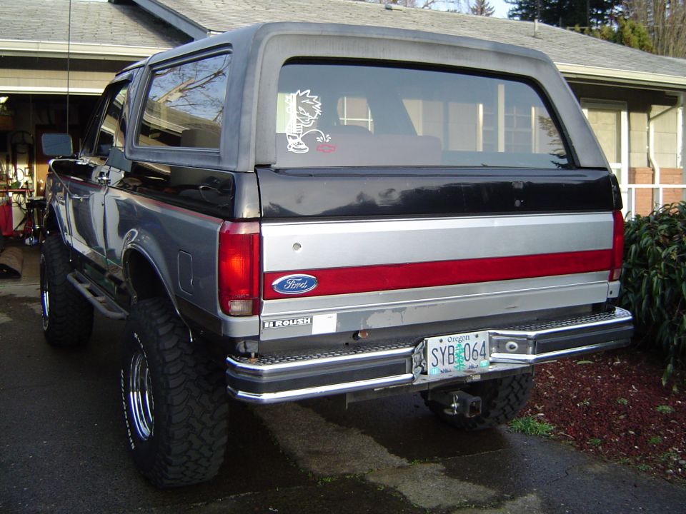 Silver and black lifted Ford Bronco rear three-quarter view in a driveway