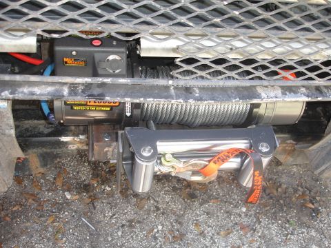 1989 Ford Bronco - Close-up of a WARN winch and tow strap mounted on a vehicle's front end.