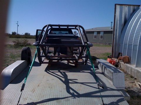 1994 Ford Bronco - A custom off-road buggy frame is strapped to a trailer, ready for transport.