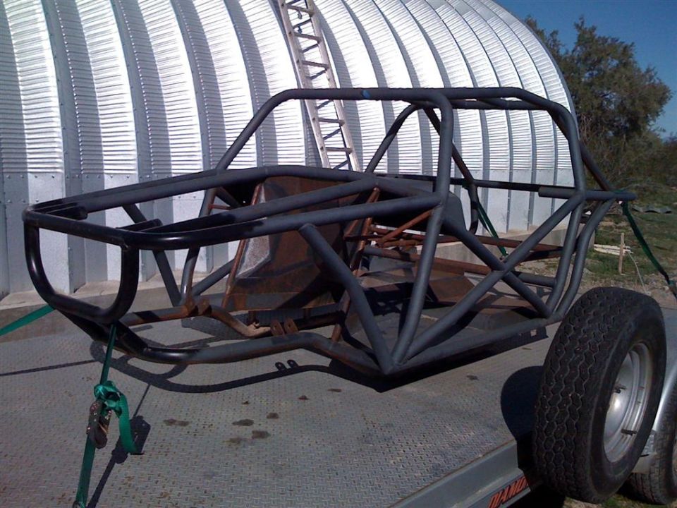 Off-road buggy frame on trailer, side view. Supermotors.net logo visible