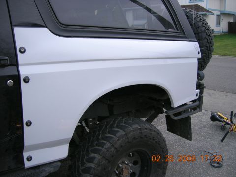 1996 Ford Bronco - The rear quarter panel of a Ford Bronco shows off its large tires and white fender flares.