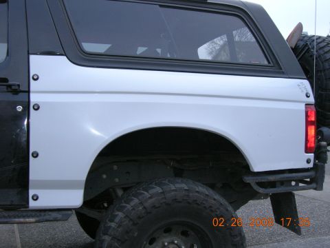 1996 Ford Bronco - Rear view of a white Ford Bronco, showing its quarter panel, fender, and off-road tire.