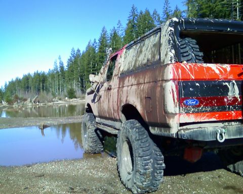 1989 Ford Bronco - Muddy 1989 Ford Bronco after off-roading near a body of water.