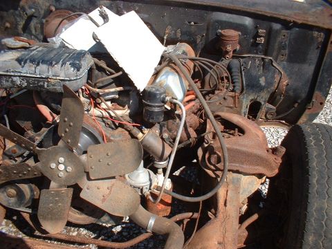 1963 Ford Galaxie - The engine bay of a heavily rusted vehicle shows its internal components, including the radiator and fan.