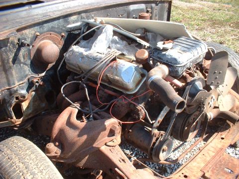 1963 Ford Galaxie - The engine bay of a 1963 Ford Galaxie reveals a V8 engine with visible rust and a cooling fan.