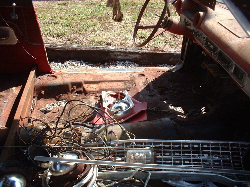 1963 Ford Galaxie interior showing rusted floor, dashboard, steering wheel, and loose wiring