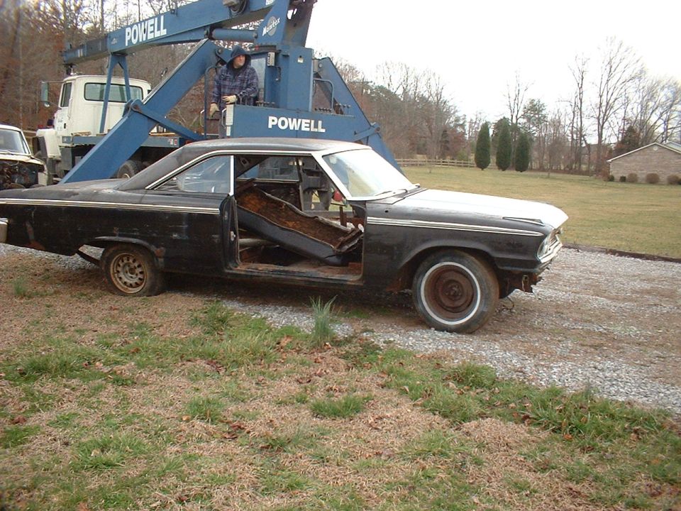 Black 1963 Ford Galaxie coupe, side view, interior removed, being towed