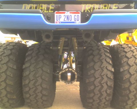 1979 Ford Bronco - This blue truck features dual rear wheels and custom text above the license plate reading 'DOUBLE TROUBLE'.