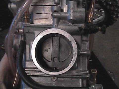 2007 Yamaha YZ450F - Close-up view of a motorcycle carburetor, showing internal components and external fuel lines.