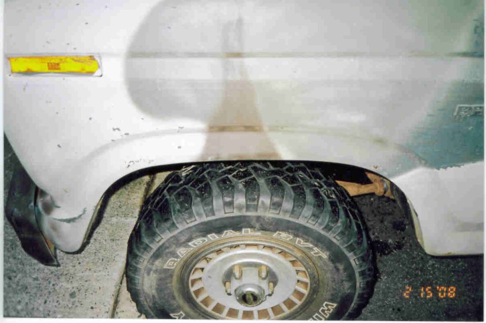 White truck front fender and wheel arch with amber marker light and mud-terrain tire