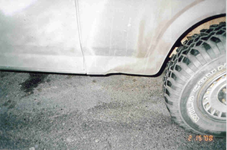 White truck rocker panel and mud-terrain tire in wheel arch, close-up