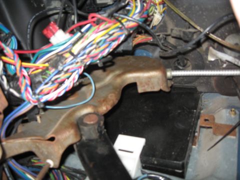 1990 Ford Bronco - A complex wiring harness is visible in the interior of a vehicle, with a metal bracket and cable also in view.