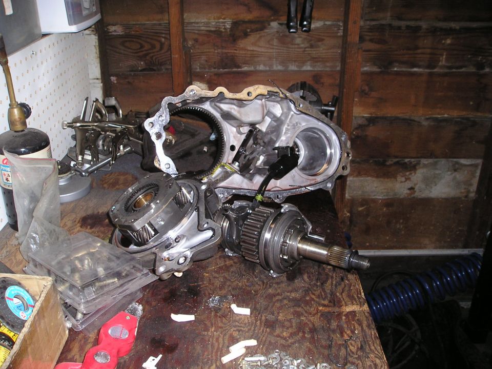 Disassembled transfer case with gears and housing on a wooden workbench