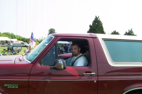 1993 Ford Bronco - Man sits in the driver's seat of a red 1993 Ford Bronco with a white top.