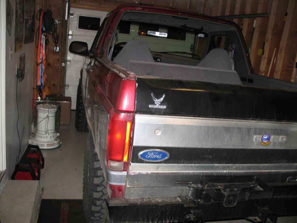 Rear of a red and black Ford Bronco parked in a garage. Has a Ford logo and an Air Force badge