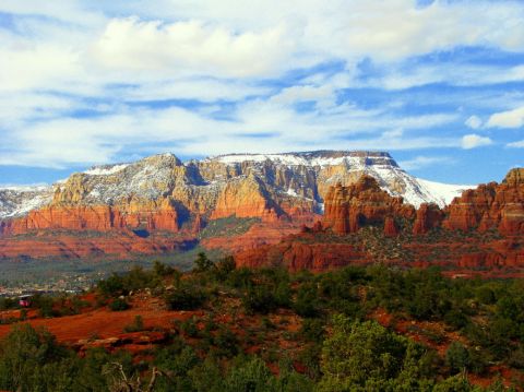 1983 Jeep CJ7 - A scenic view of Sedona's red rocks, with snow dusting the mountain peaks under a bright blue sky.