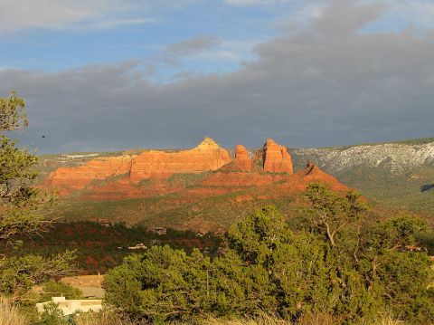 1983 Jeep CJ7 - The iconic red rocks of Sedona stand tall against a dramatic sky, with desert flora in the foreground.