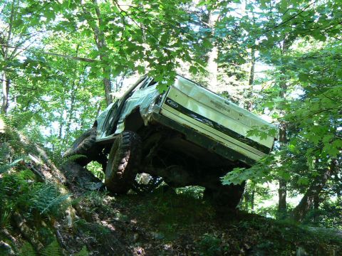 1995 Ford Bronco - This 1995 Ford Bronco is navigating a challenging off-road trail through a dense forest.
