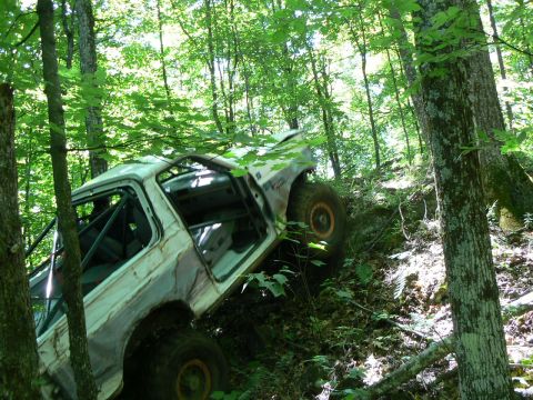 1995 Ford Bronco - This vehicle appears to be stuck on a steep, wooded slope with its doors open.