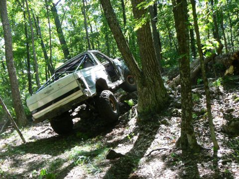 1995 Ford Bronco - This modified 1995 Ford Bronco navigates a challenging off-road trail through a dense forest.