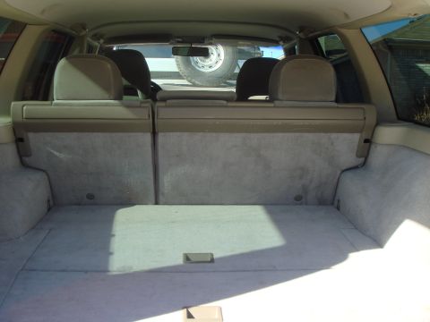 1998 Volvo V70 - The cargo area of a station wagon is shown from the rear, with folded seats and a spare tire visible through the back window.