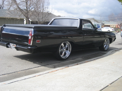 1970 Ford Ranchero - A black 1970 Ford Ranchero is shown from the rear 3/4 angle, custom chrome wheels and a tonneau cover.