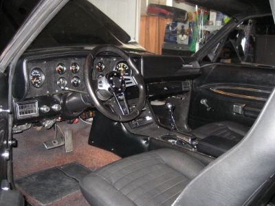 1970 Ford Ranchero - The interior of a car shows custom gauges and a steering wheel, with black seats and carpeting.