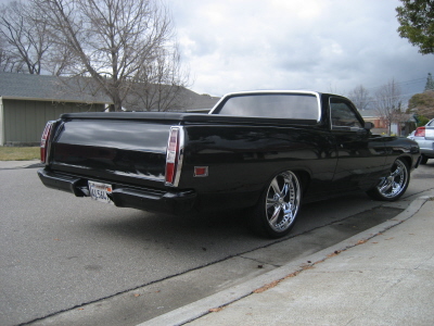 1970 Ford Ranchero - A black 1970 Ford Ranchero is shown from the rear quarter angle, parked curbside on a cloudy day.