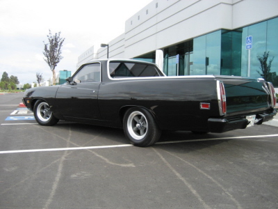 1970 Ford Ranchero - This black 1970 Ford Ranchero is parked in a lot outside a modern building.