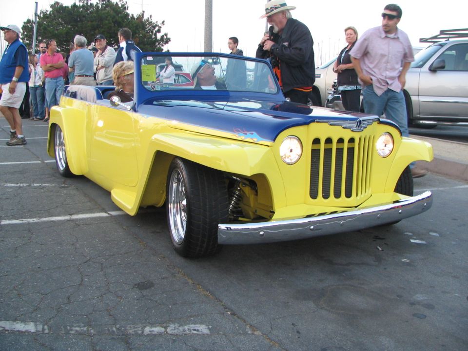 Yellow and blue customized Jeepster with flames on the hood, lowered suspension, and chrome bumper