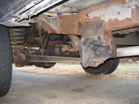 1978 Ford Bronco - The underside of a vehicle reveals significant rust on the frame and suspension parts.