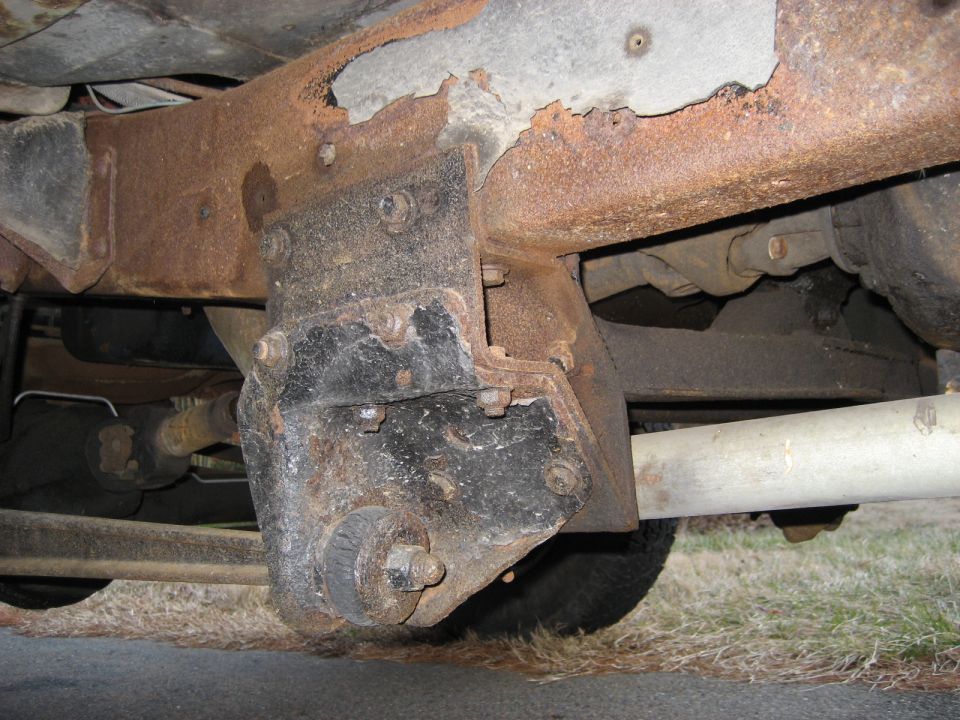 rusted frame rail with suspension bracket and exhaust pipe