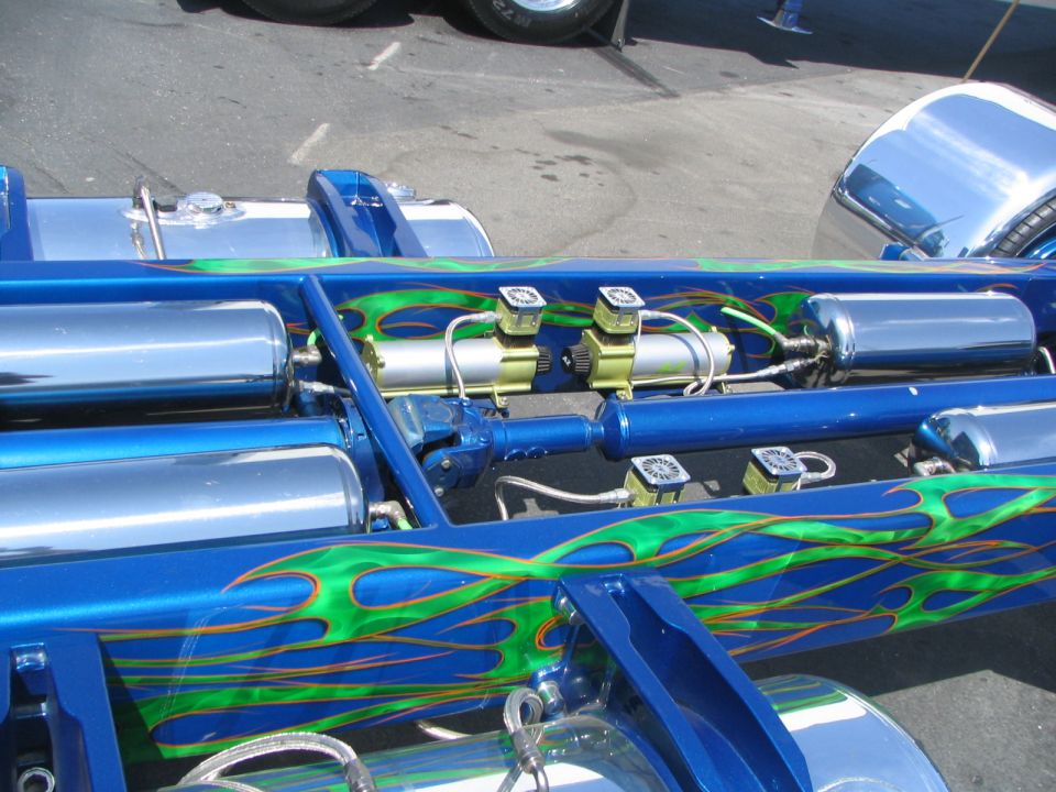 Blue chassis with green flames, chrome air tanks, and yellow air compressors