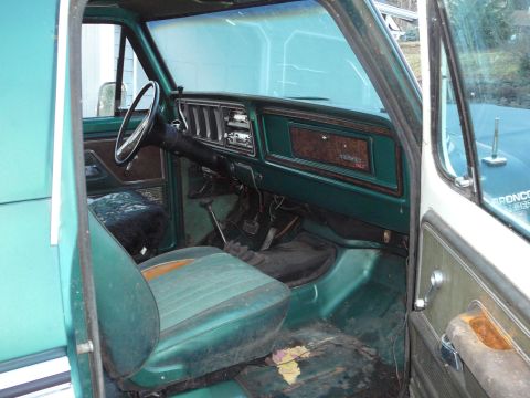 1978 Ford Bronco - The interior of a 1978 Ford Bronco, green upholstery and wood-grain trim on the dashboard.