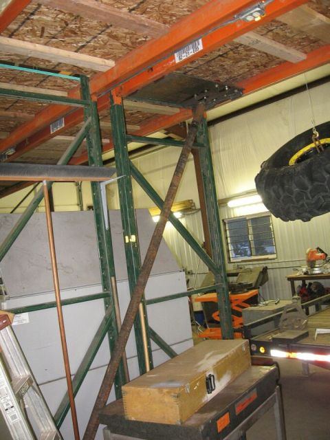 1986 Ford Ranger - A cluttered workshop scene shows industrial shelving, a spare tire suspended from above, and various tools and storage containers.
