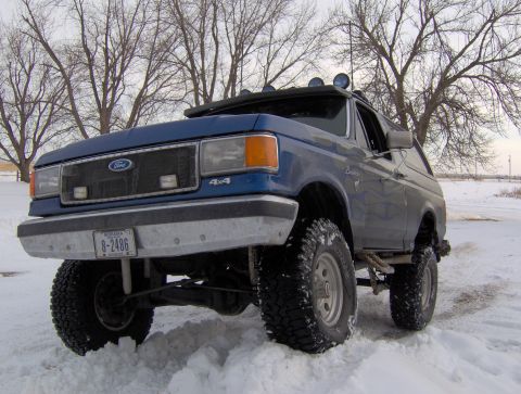 1987 Ford Bronco - Blue 1987 Ford Bronco parked in a snowy landscape with bare trees.