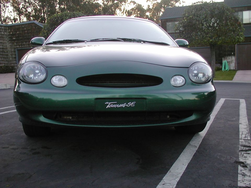 Front view of dark green Ford Taurus SE sedan parked in a lot with Taurus SE plate