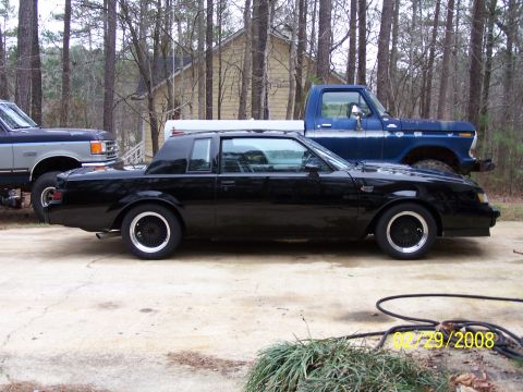 1979 Ford F-150 - A black coupe and a blue pickup truck are parked outdoors in front of a house.