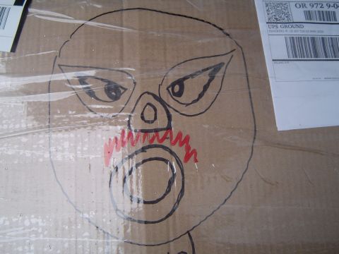 1989 Ford Bronco - A drawing of a face adorns a cardboard box, partially obscured by plastic wrap and a UPS shipping label.