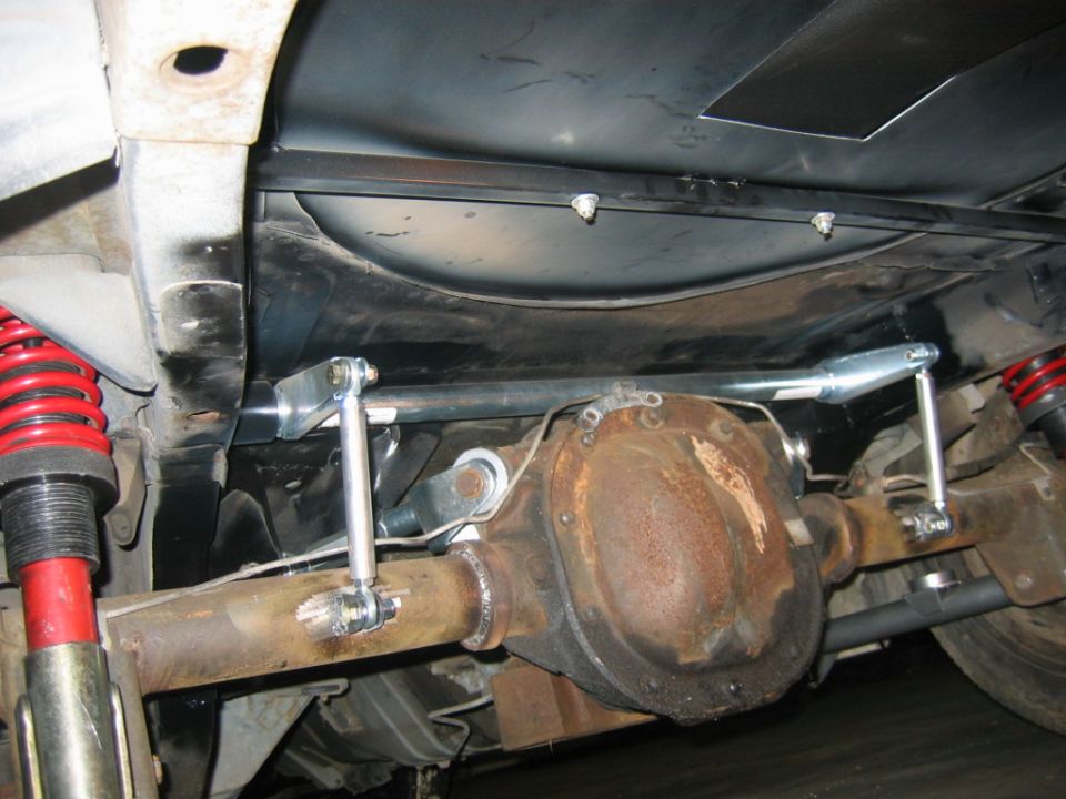 Underside view of a car's rear axle with red coilover shocks and aftermarket suspension links