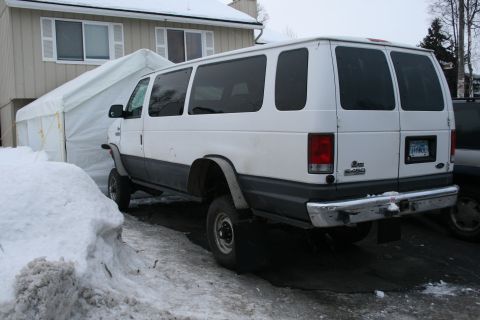2003 Jeep TJ - A white van is parked in a snowy area next to a temporary tent structure.
