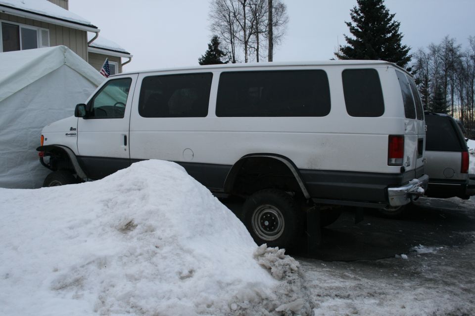 White van with dark tinted windows parked in snow, side view