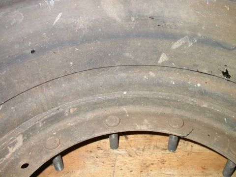 1990 Ford Bronco - Extreme close-up of a dirty steel beadlock ring seated on a tire bead, with threaded studs protruding through the ring's bolt holes and a p…