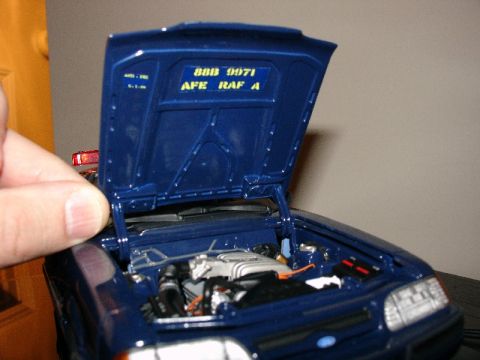 2003 Ford Crown Victoria - Close-up of a blue model car's engine bay, with the hood open revealing the engine and interior details.