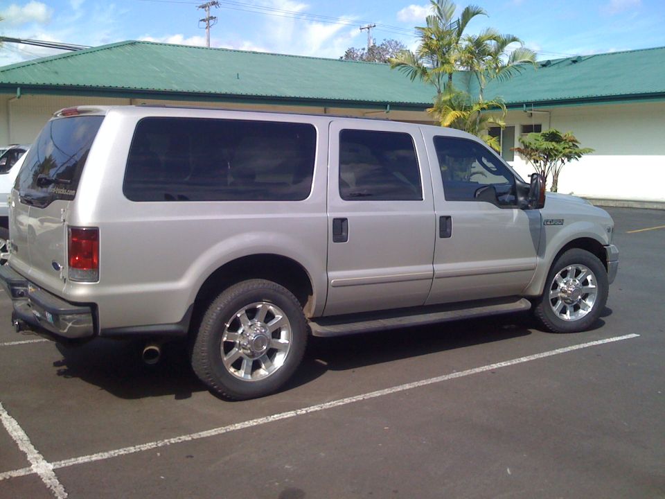 Silver Ford Excursion SUV, rear 3/4 passenger side view, parked outdoors