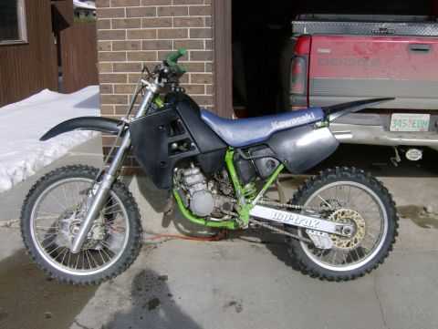 1989 Chevrolet Blazer - A Kawasaki dirt bike is parked in front of a red Dodge pickup truck.