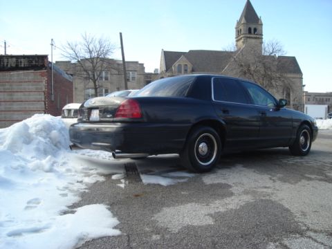 2000 Ford Crown Victoria - Rear view of a black 2000 Ford Crown Victoria parked next to a snowbank on a sunny day.